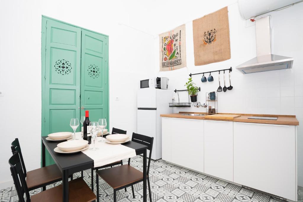 a kitchen with a table and a green door at Petite California Dos de Mayo in Seville