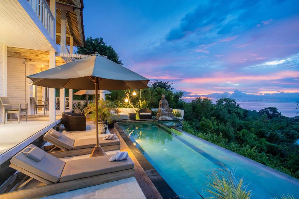 een zwembad met stoelen en een parasol bij The Puncak Private Villa in Nusa Lembongan