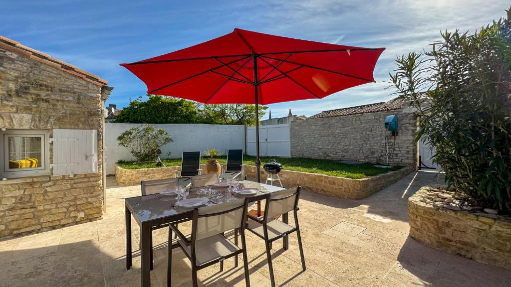 a table with a red umbrella on a patio at Dans le centre du village d'ARS EN RE, charmante villa bien décorée in Ars-en-Ré