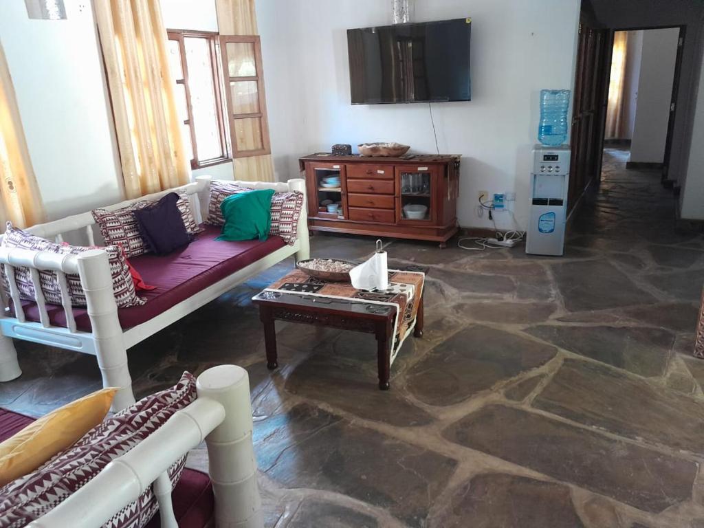 een woonkamer met een bank en een tv bij Lion Garden Villa 7 in Malindi