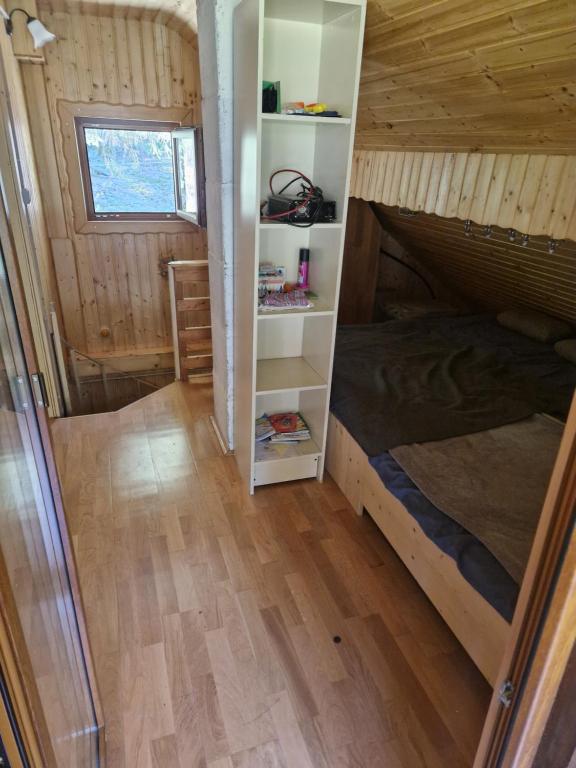 1 dormitorio en una casa pequeña con cama y estanterías en Koča v gozdu en Bled