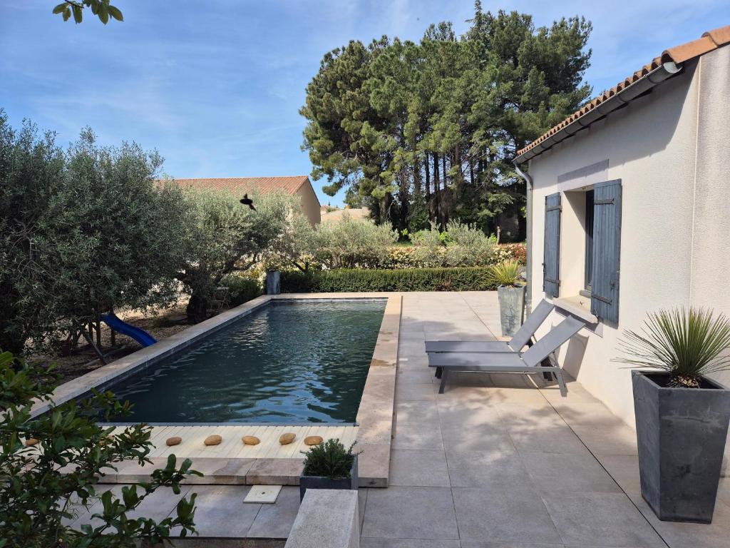 una piscina en un patio con una casa en Villa avec piscine dans un domaine viticole, en Domazan