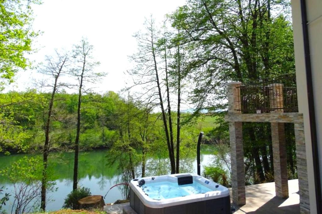 un jacuzzi en un patio junto a un río en House Kolpa Paradise Whirlpool and Sauna, en Metlika