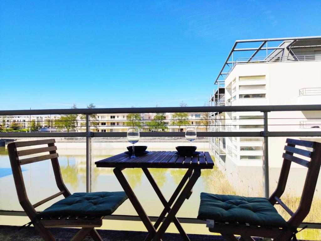 - une table avec 2 chaises et des verres à vin sur le balcon dans l'établissement Joli appartement aux Minimes avec Parking, à La Rochelle