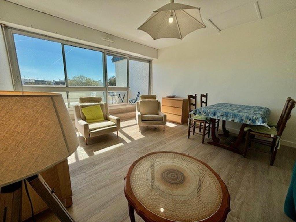 Elle comprend un salon meublé et une grande fenêtre. dans l'établissement Appartement T2 50m² - Balcon Sud - Centre Quiberon - Proche Plage - Parking - TV - 4 Pers - FR-1-478-191, à Quiberon