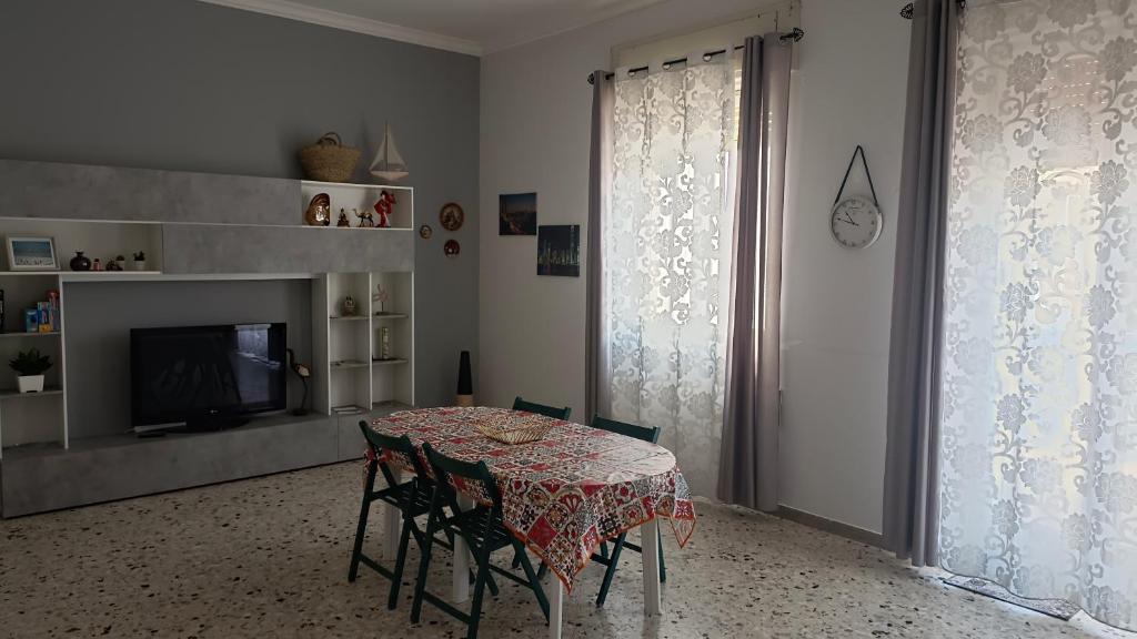ein Esszimmer mit einem Tisch, Stühlen und einem TV in der Unterkunft APPARTAMENTO Fiori di MELOGRANO in Trapani