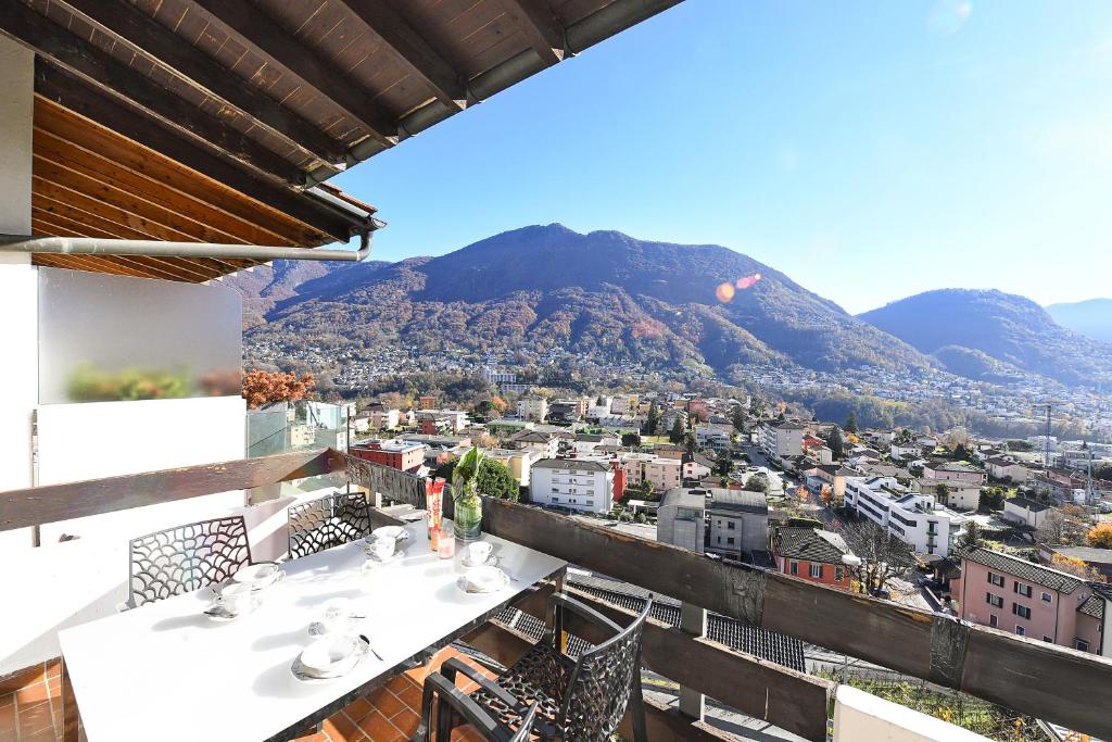 balcón con mesa, sillas y montaña en Feeling Home Lugano - Happy Rentals, en Canobbio
