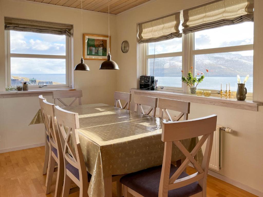 a dining room with a table and chairs and two windows at Sea & Mountain View 3 Bedroom in Leynar