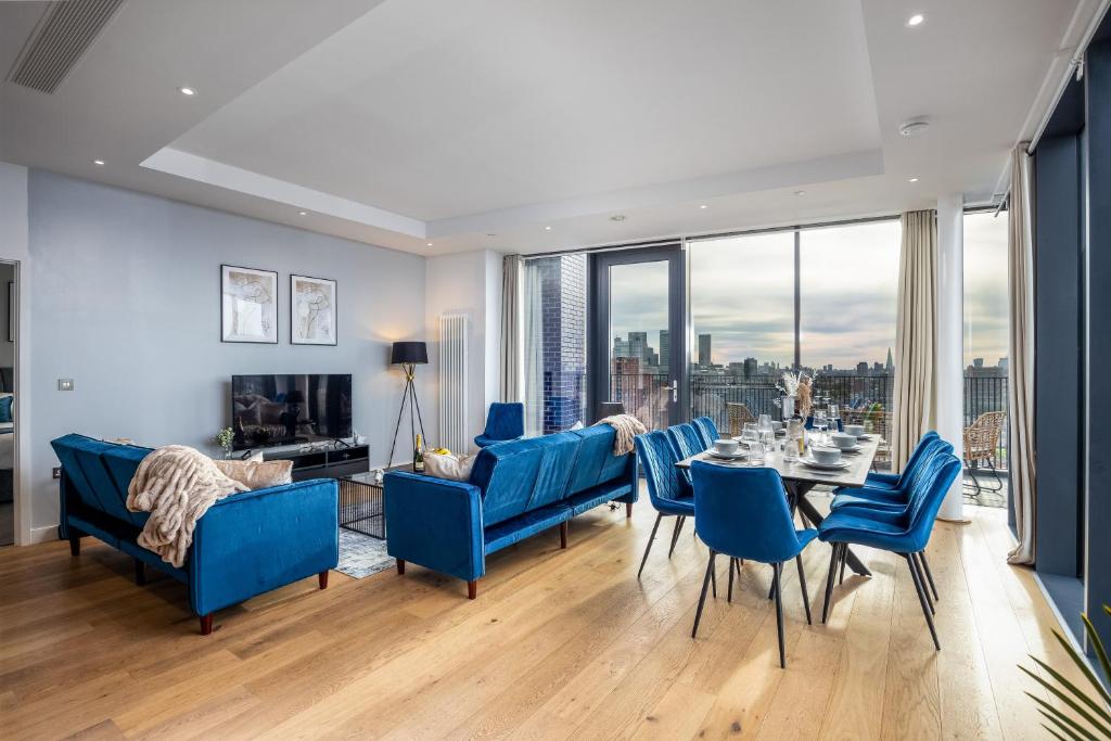 Luxury & Spacious 2 BR APT with City Views في لندن: غرفة طعام مع كراسي زرقاء وطاولة مطلة