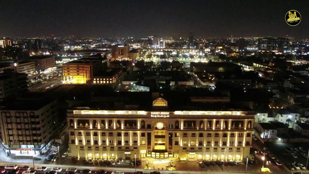 a lit up building with a city at night at Sunset Jeddah in Jeddah