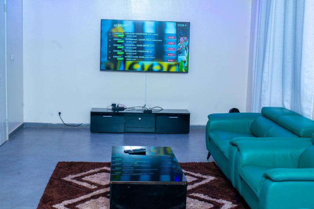 sala de estar con sofá azul y TV en Heberease Résidences, en Dakar