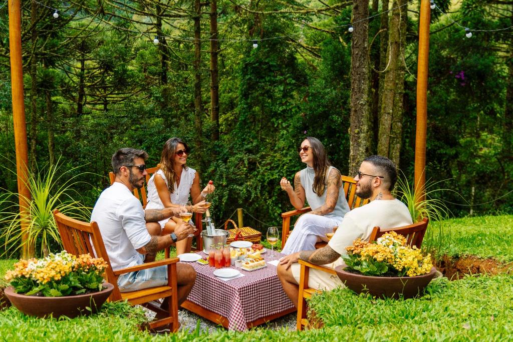 a group of people sitting around a table in the grass at Pousada Casa Campestre in Gonçalves