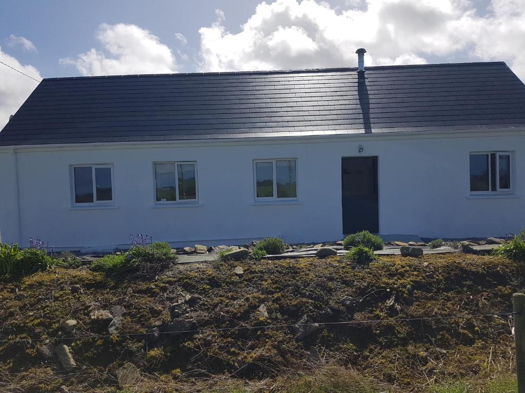 a white house with a black roof at Beautiful 3-Bed House close to Ballybunion in Tralee