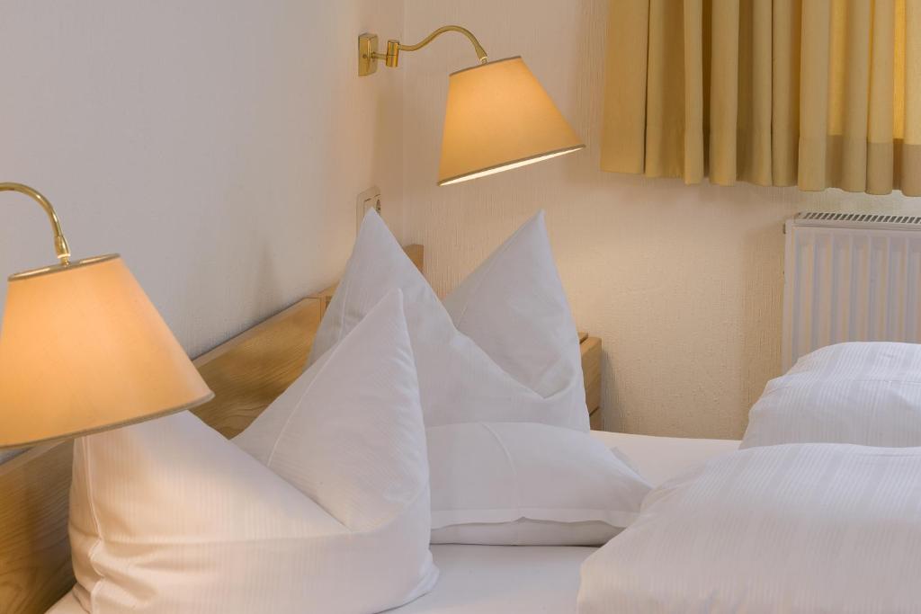 a bedroom with white pillows on a bed with two lamps at Hotel Parkfrieden in Timmendorfer Strand