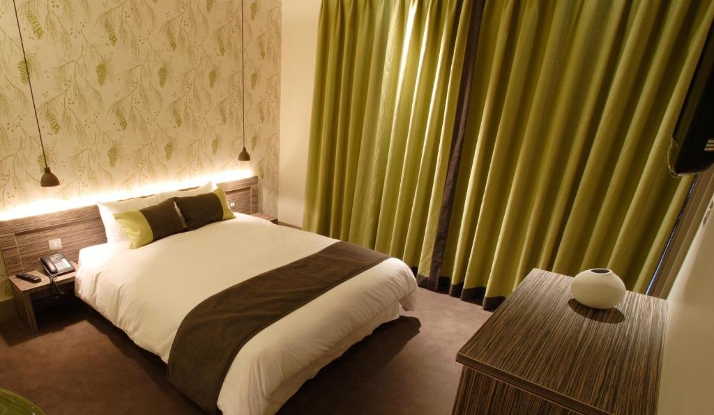 a bedroom with a bed and a large window with green curtains at Hotel Bosco in Kingston upon Thames