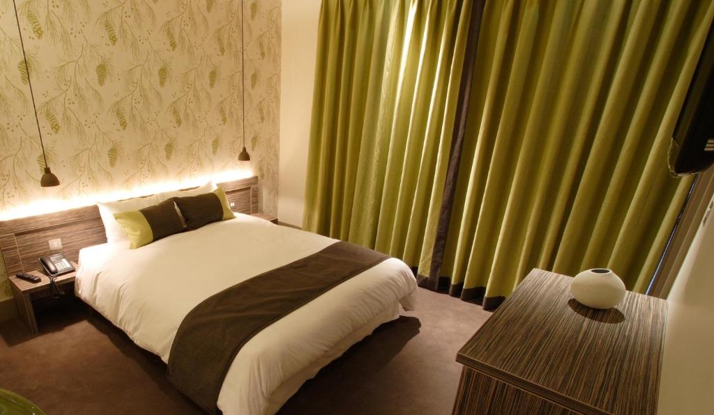 una camera da letto con un letto e una grande finestra con tende verdi di Hotel Bosco a Kingston upon Thames