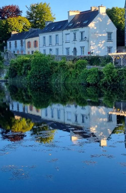 un bâtiment blanc avec une réflexion dans un corps d'eau dans l'établissement The Place to B&B, à Huelgoat