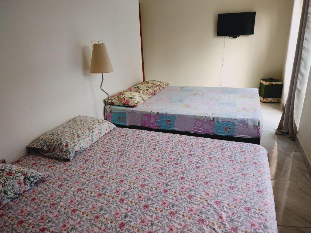 Habitación con 2 camas individuales y TV. en Casa no Guarujá com 1 quarto en Bertioga