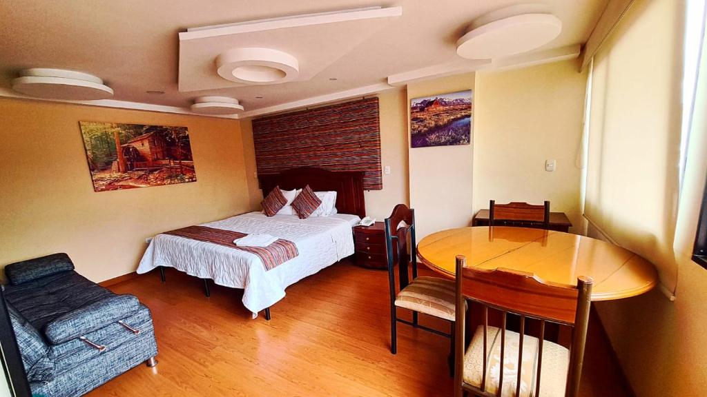 a bedroom with a bed and a table and a dining room at Hotel Xilon Resort Plaza in Pasto