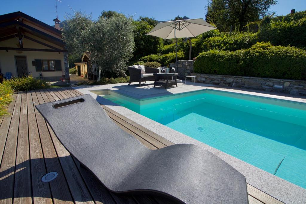 CastelveccanaにあるOasi di Castelveccana Apt Pool and Viewのテーブルと傘付きのスイミングプール