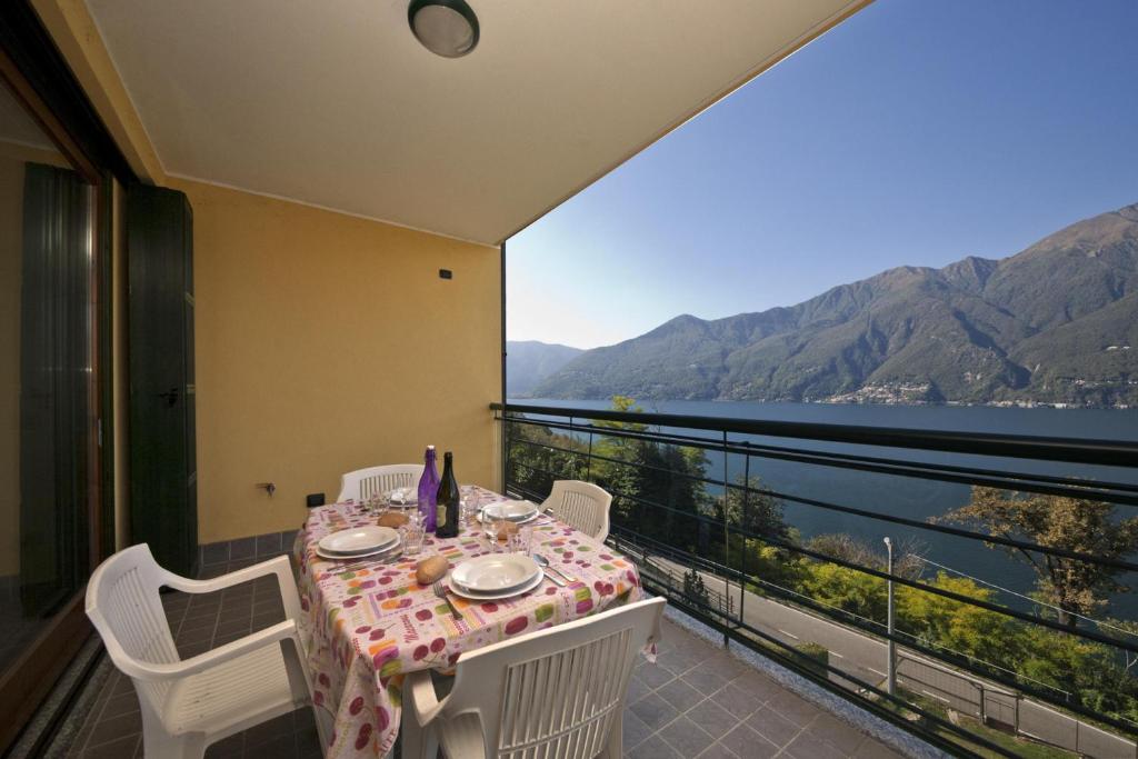 una mesa y sillas en un balcón con vistas al agua en Va Pensiero sul lago Stunning View, en Tronzano Lago Maggiore