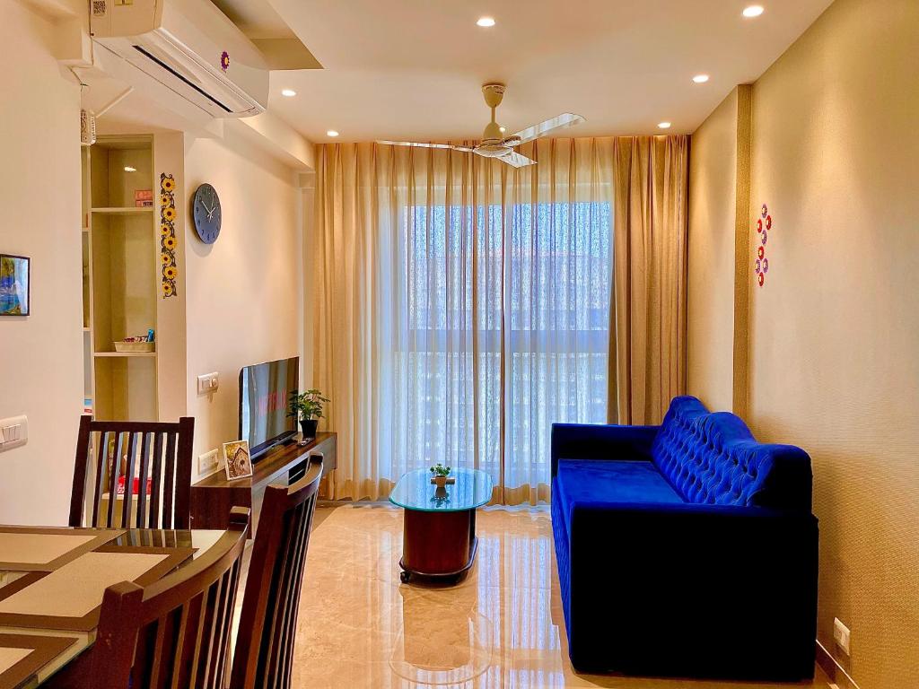 a living room with a blue couch and a table at City Nest 1 BHK in Hiranandani Powai (C) in Mumbai
