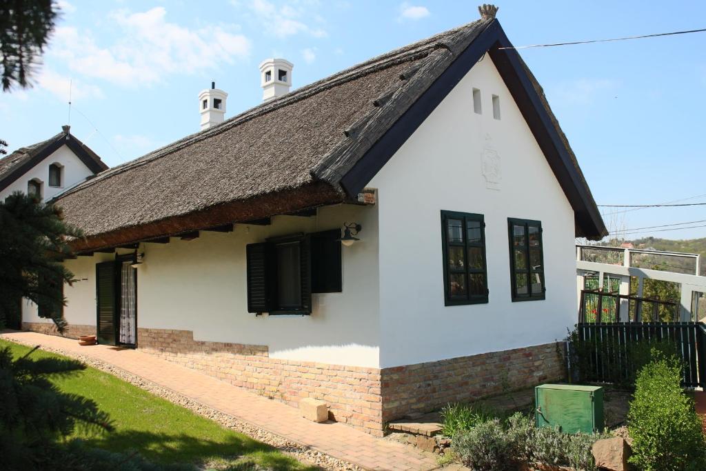 une maison blanche avec un toit noir dans l'établissement Rozika guesthouse - Sukoró, à Sukoró