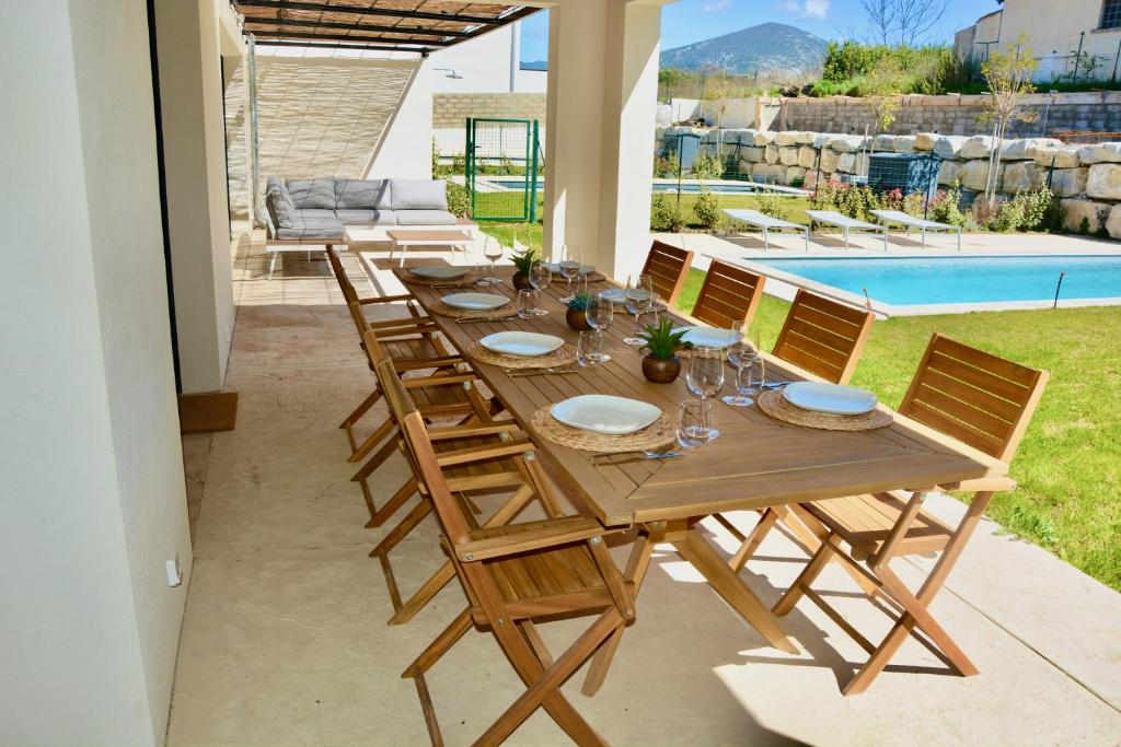 een lange houten tafel met stoelen en een zwembad bij Villa Jilie in Malaucène