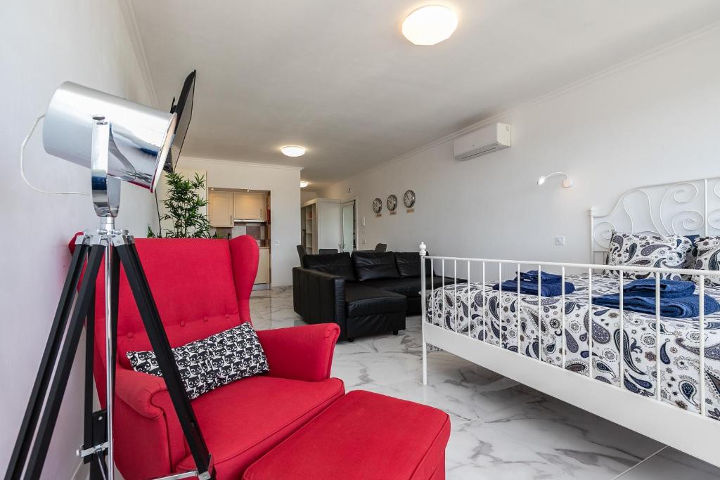 Una sala de estar con una silla roja y una cama. en T0 Vilamoura Downtown, en Vilamoura