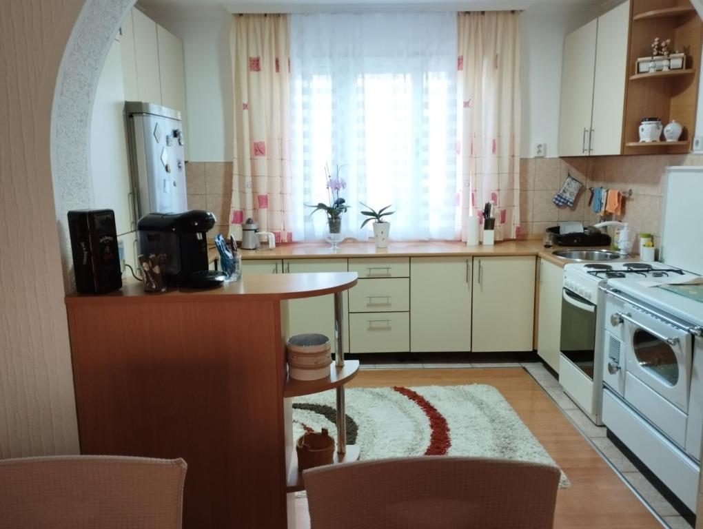 une cuisine avec des placards blancs et une table avec un tapis dans l'établissement Apartman Unac, à Drvar