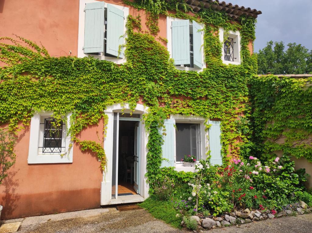 une maison recouverte de lierre avec une porte dans l'établissement La Rose des Claux, à Fayence