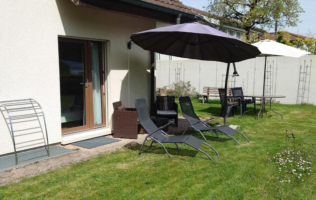 a patio with two chairs and an umbrella at Maison Champperbou in Haut-Vully