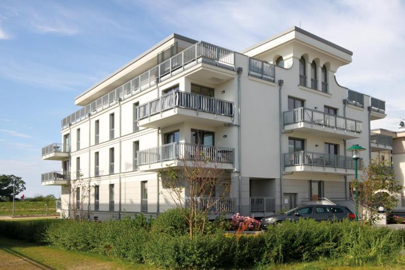 ein weißes Gebäude mit einem davor geparkt in der Unterkunft Villa Deichgraf in Börgerende-Rethwisch