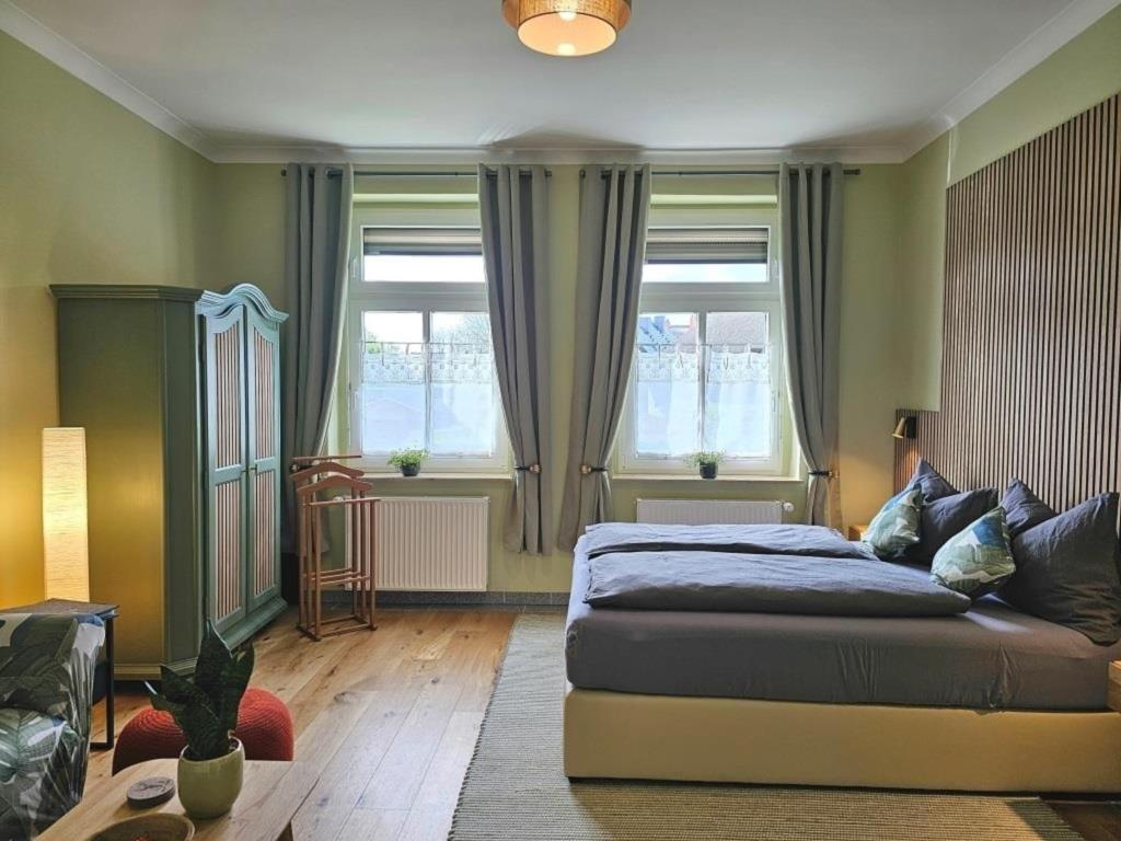 1 dormitorio con cama, sofá y ventanas en Ferienhof SchilfMeer - Fewo "Seepferdchen", en Dorf Körkwitz