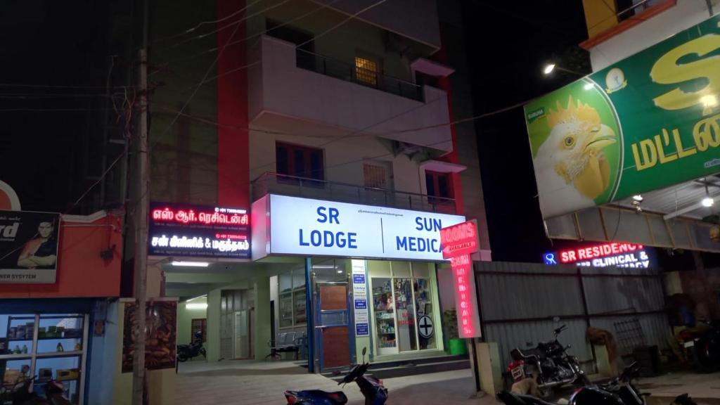 un groupe de bâtiments avec des panneaux de néons la nuit dans l'établissement SR RESIDENCY, à Chennai