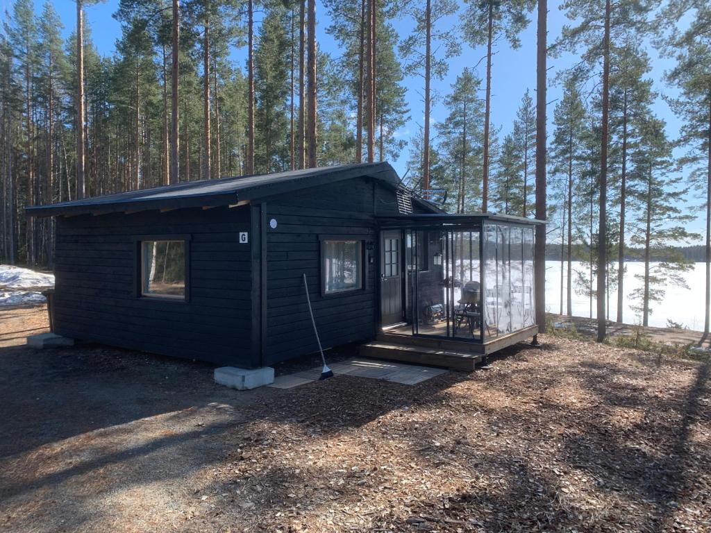 uma pequena casa preta no meio de uma floresta em Lakeland BoxCabin em Viitasaari