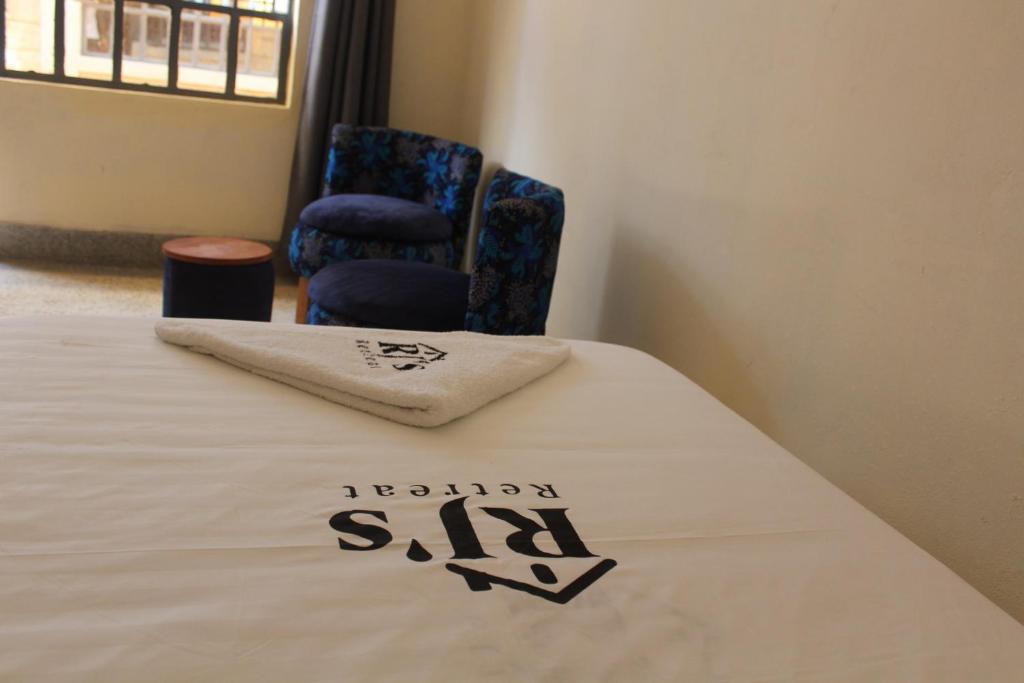 a hotel room with a bed and a chair at RJ's Retreat Migwani Town in Kathera