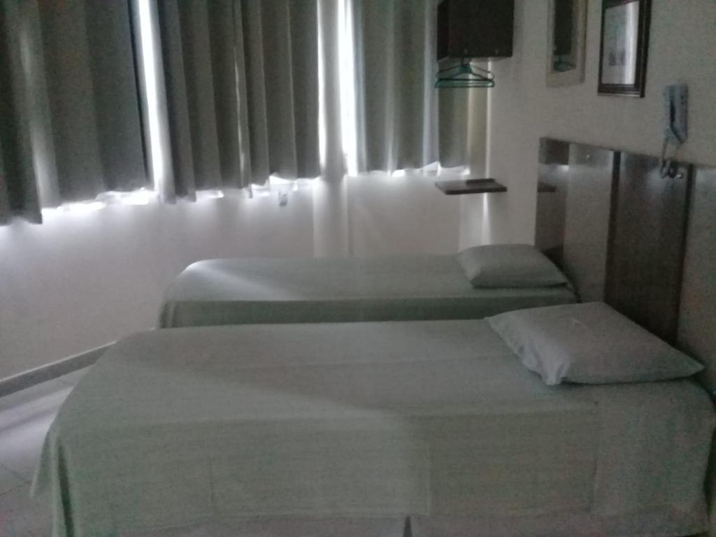 two beds in a white room with windows at Hotel Rio Branco in Jequié