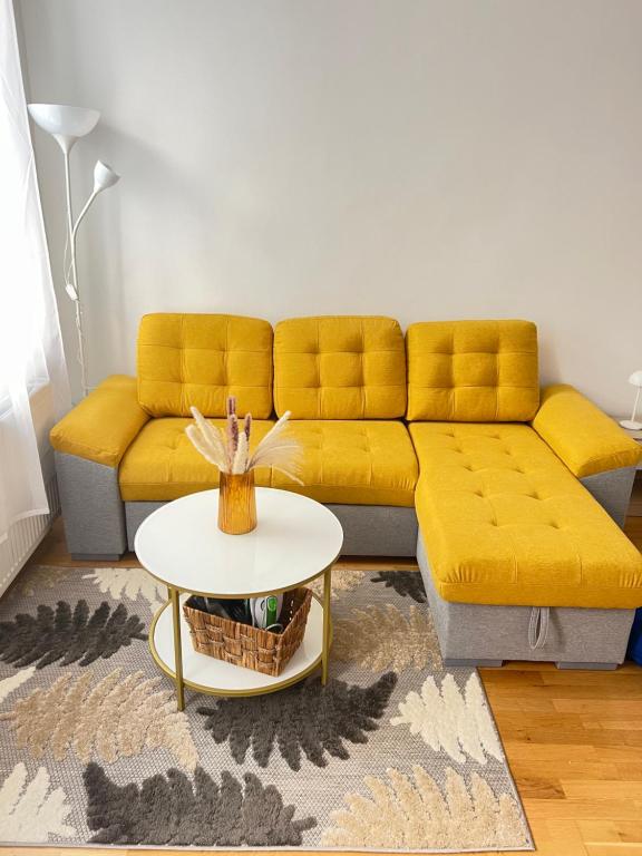 Una sala de estar con un sofá amarillo y una mesa. en Top Location, en Viena