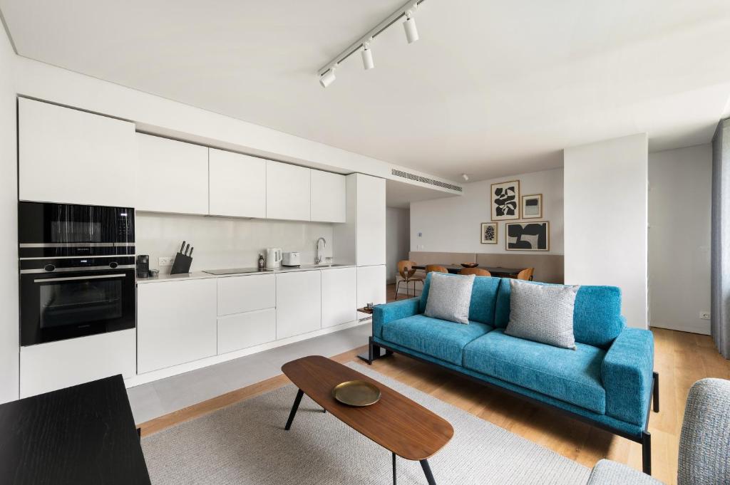 Mirabilis Apartments - LX Living في لشبونة: غرفة معيشة مع أريكة زرقاء ومطبخ