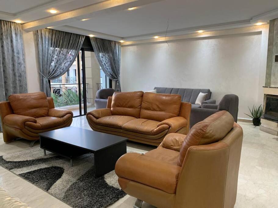 Una sala de estar con un sofá y sillas y una mesa. en Beautiful 3BR apartment in Hay Riad Rabat, en Rabat