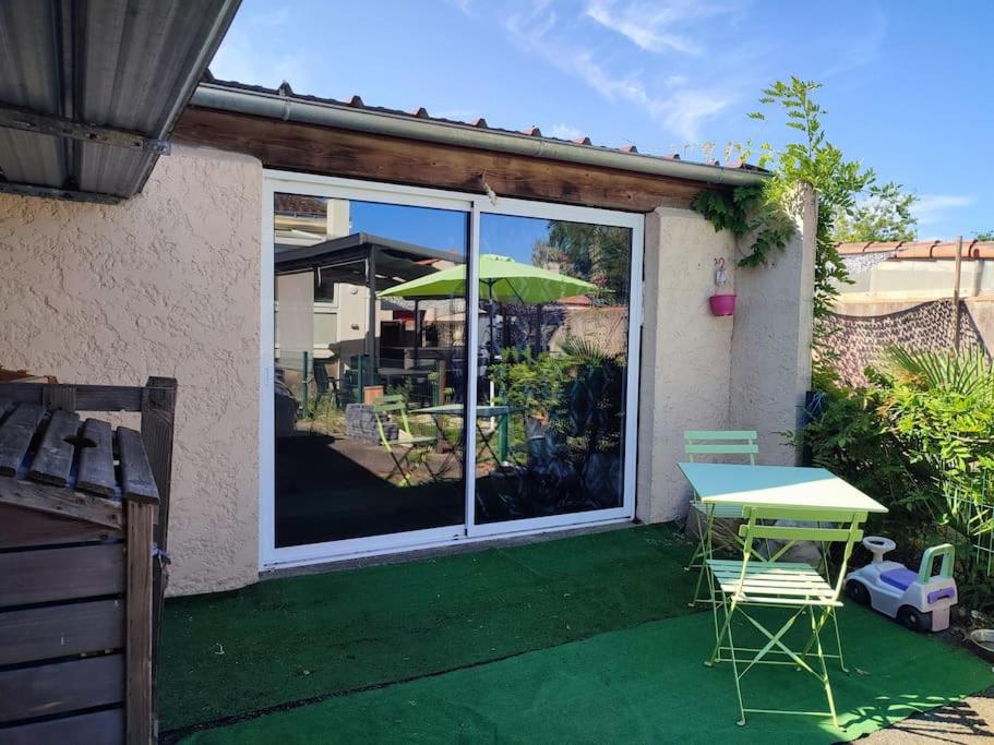 een patio met een tafel en stoelen en een parasol bij tiny house in Les Sorinières