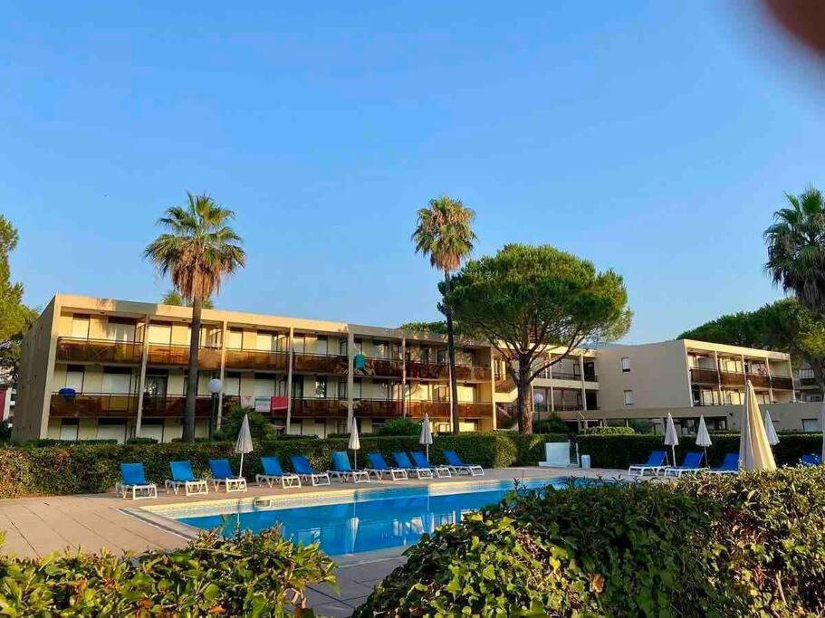 un hôtel avec une piscine, des chaises et des palmiers dans l'établissement Mandelieu / Appart Climatisé 4 prsn RDC / Piscine, à Mandelieu-la-Napoule