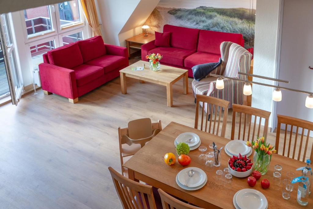 Ferienzentrum Wenningstedt في فينينغستيدت: غرفة معيشة مع أريكة حمراء وطاولة