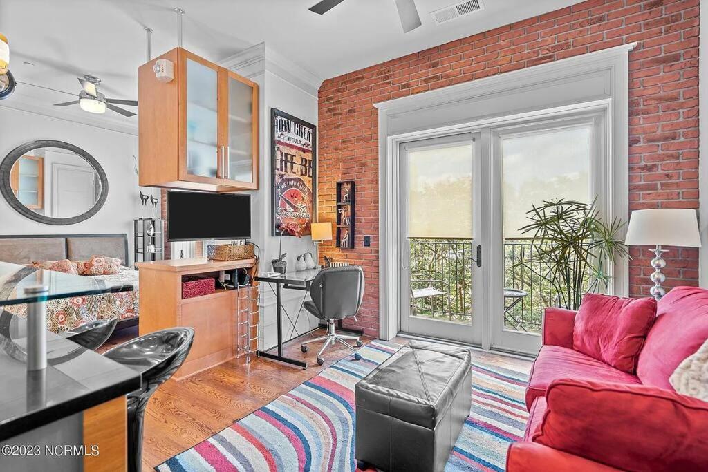 a living room with a red couch and a brick wall at Downtown Condo*Balcony*River*Pet Friendly*Beach in Wilmington