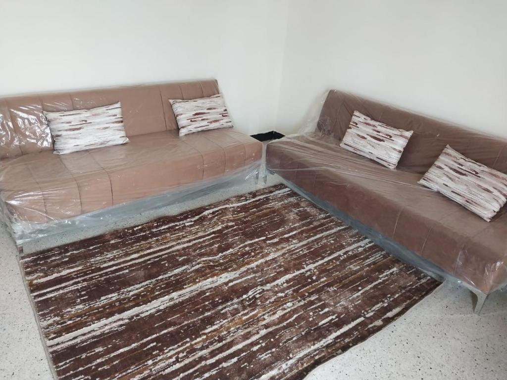Sofá marrón con 2 almohadas encima de una alfombra en Superbe appartement à louer,Hassan en Rabat