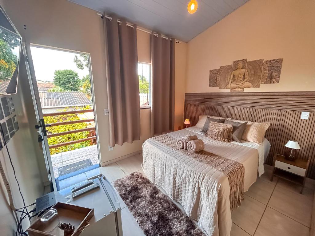 een slaapkamer met een bed en een groot raam bij Villa Madeira in Alto Paraíso de Goiás