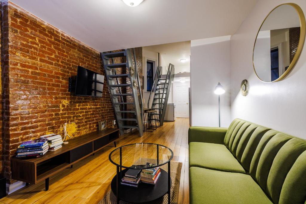 a living room with a green couch and a brick wall at Experience the Vibrant Energy of City Living in New York