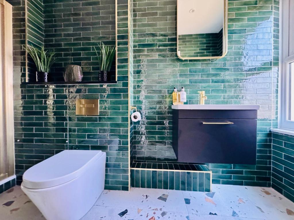 baño con aseo y pared de azulejos verdes en "The Penthouse Newquay" by Greenstay Serviced Accommodation - Stunning 3 Bed Apt With Parking & Sun Terrace - The Perfect Choice For Families, Small Groups & Business Travellers - Newly Refurbished - Close To Beaches, Shops & Restaurants, en Newquay