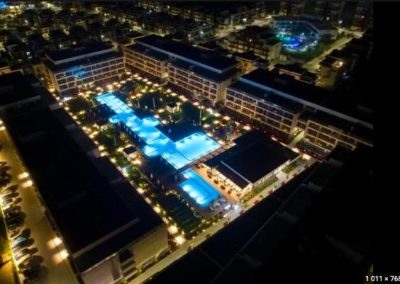 an aerial view of a building with a pool at night at Courtyard Long Beach Holiday Resort in Iskele